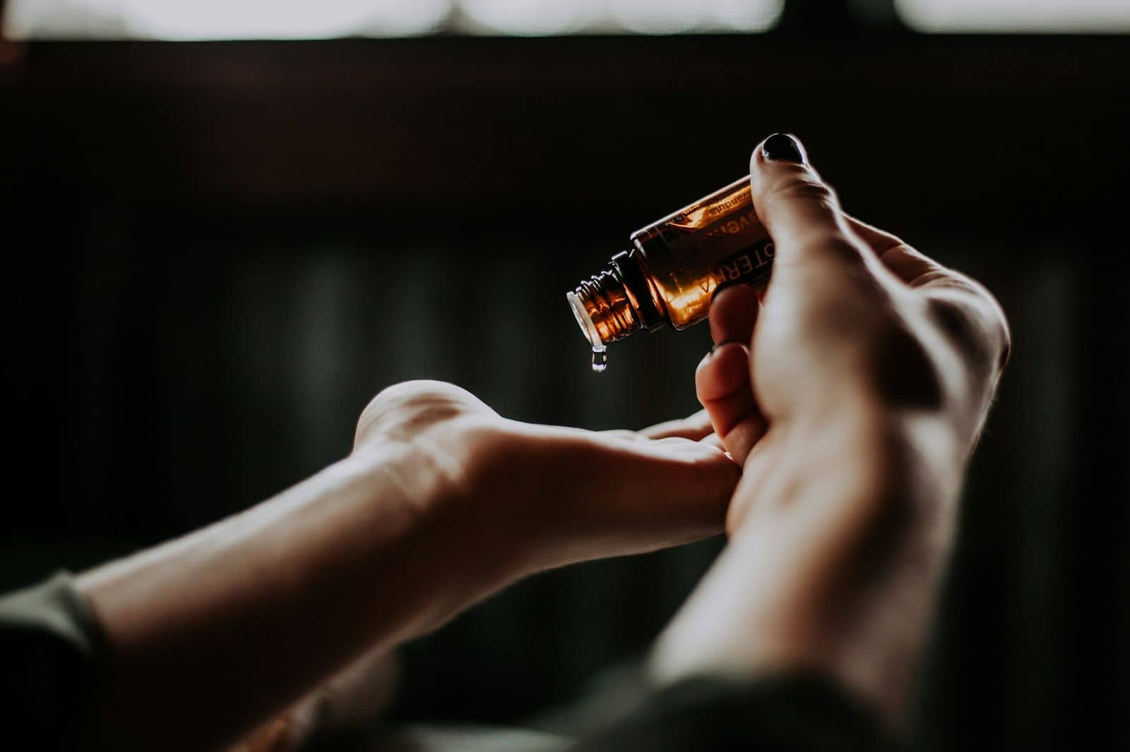 Hands holding a dropper of serum in low light