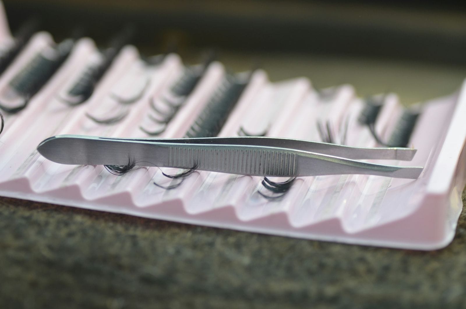 Tweezers resting on a tray of lash extensions