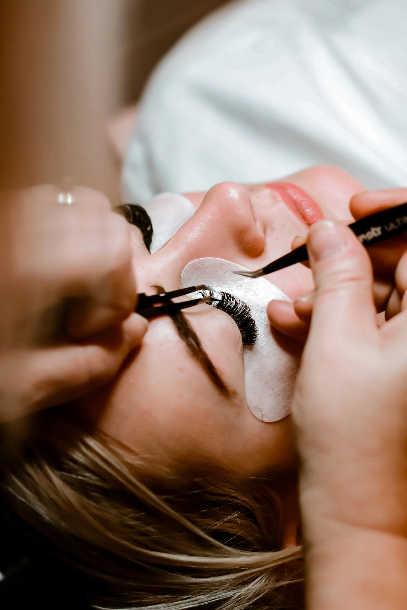 Lash artist placing a classic extension with fine tweezers